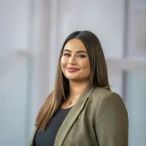 Junge Frau im grünen Blazer und dunklem Oberteil