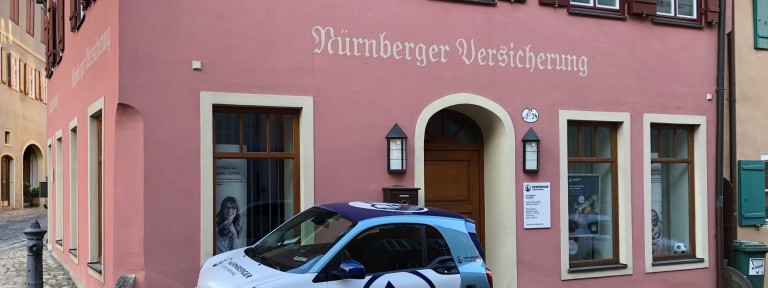 rosa Haus mit der Aufschrift Nürnberger Versicherung und Auto 