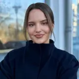 Junge Frau mit braunen Haaren und Zopf steht vor einem Gebäude