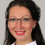 Frau mit langen dunklen Haaren und Brille
