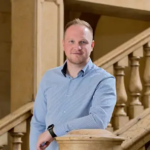 Lächelnder Mann im blauen Hemd steht auf einer Treppe