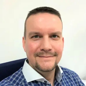 Mann mit sehr kurzen Haaren und blau kariertem Hemd