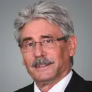 Mann mit vollen grauen Haaren und Schnauzbart