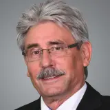 Mann mit vollen grauen Haaren und Schnauzbart