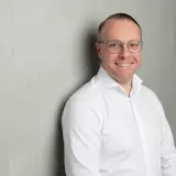 Mann mit weißem Hemd und Brille lächelt