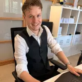 Mann mit Hemd sitzt an einem Schreibtisch vor seinem Laptop