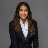 Frau mit langen braunen Locken und dunklem Blazer
