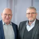 zwei Männer mit Brille und Anzug stehen nebeneinander