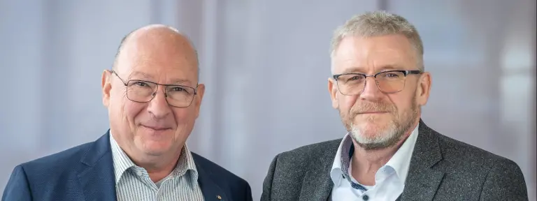 zwei Männer mit Brille und Anzug stehen nebeneinander