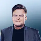 Junger Mann in grauem Anzug und dunklen Pullover