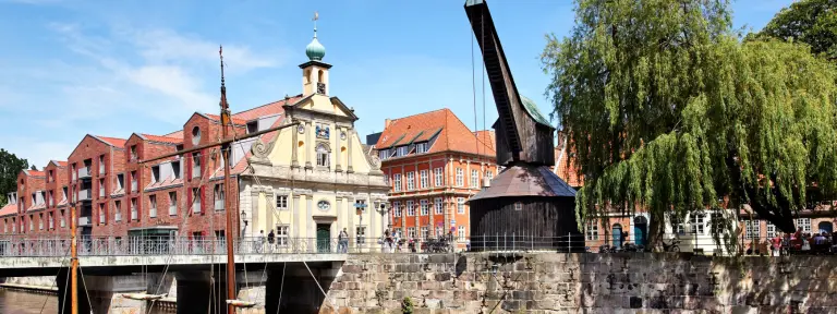 Ein Fluss mit Brücke und einem Kran bei sonnigem Wetter in Lüneburg