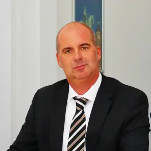 Mann mit Anzug und Krawatte sitzt am Schreibtisch