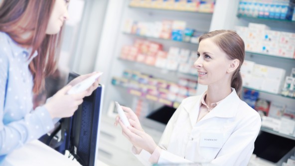 Junge Frau lässt sich von einer Frau im weißen Kittel in einer Apotheke beraten