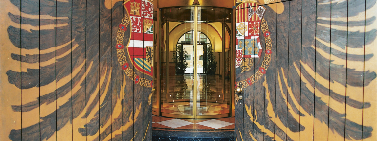 Blick auf einen schmalen Eingang in ein Gebäude mit einer Glas-Drehtür