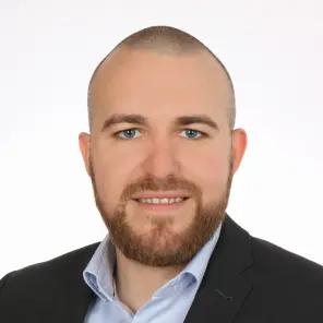 Lächelnder Mann im dunklen Blazer und hellblauen Hemd