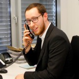 Telefonierender jüngerer Mann mit Brille