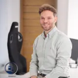 Junger Mann sitzt auf einem Schreibtisch