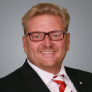 Blonder Mann mit Brille und weiß-rot gestreifter Krawatte