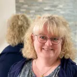 Blonde Frau mit Brille und blauer Bluse