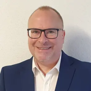 Mann im Anzug mit sehr kurzen Haaren und Brille