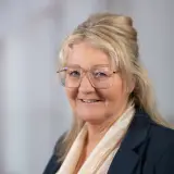 freundlich schauende Frau im Blaser mit Brille