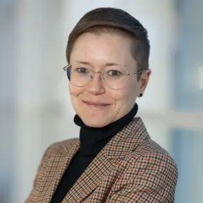 Frau mit kurzen Haaren und Brille lächelt