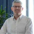 grauhaariger Mann mit Brille und weißem Hemd