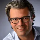 Mann mit Brille lächelt in die Kamera