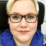 blonde Frau mit Brille lächelt in die Kamera