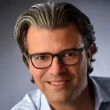 Mann mit Brille lächelt in die Kamera