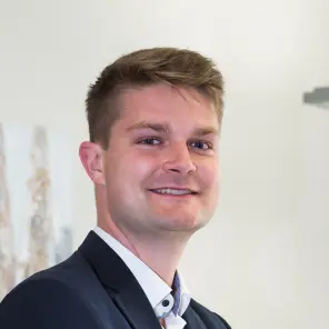 Dunkelblonder Mann mit dunkelblauem Jackett