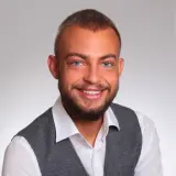 Ein lächelnder Mann mit Hemd und grauer Weste