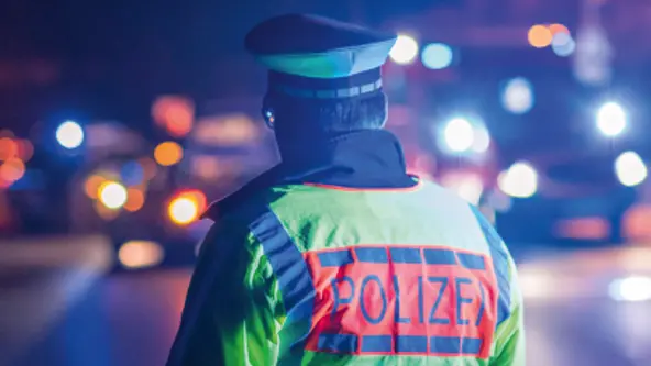 Ein Polizist in Warnweste blickt zum Verkehr