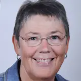 Frau mit kurzen Haaren und Brille lächelt