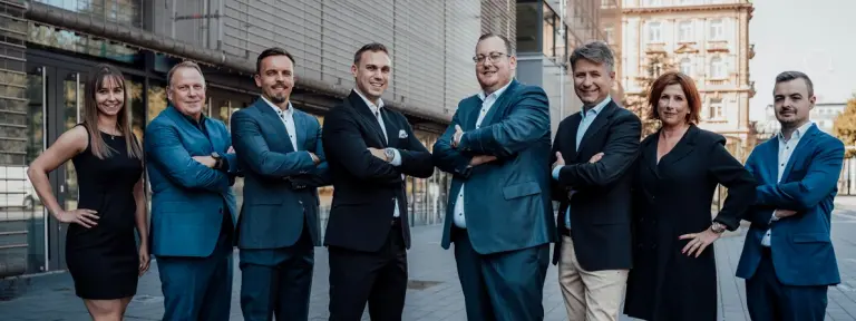 acht Personen stehen zum Gruppenbild aufgestellt nebeneinander