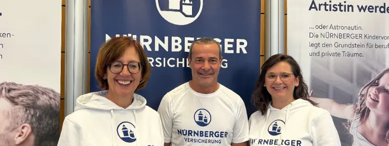 Zwei Frauen und ein Mann lächeln in die Kamera