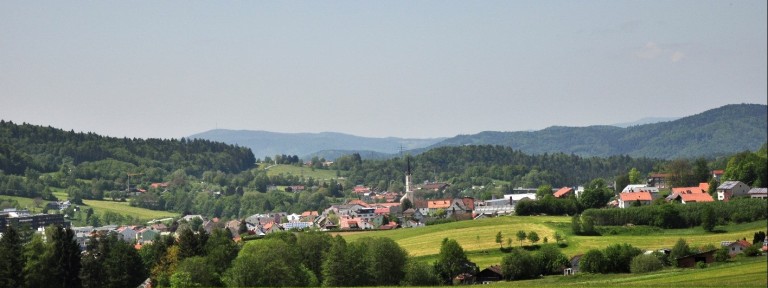 Dorf in hügeliger grüner Landschaft