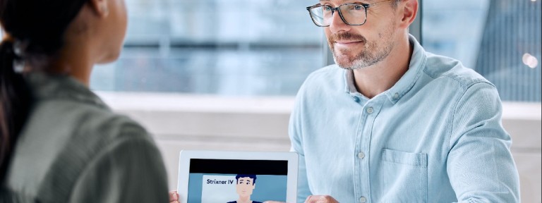 Mann mit Brille zeigt einer Frau etwas auf einem Tablet