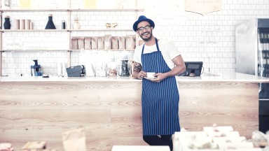 Mann mit Hut und blauer Schürze steht in einer Küche