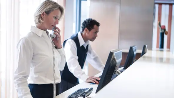 Mann und Frau stehen als Angestellte am Empfang eines Hotels