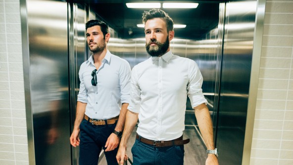 2 junge Männer in hellem Hemd laufen aus einem Aufzug