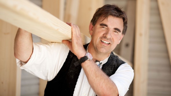 Handwerker hält Holzbalken auf seiner Schulter