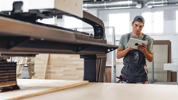 Handwerker schaut sich in seiner Werkstatt auf einem Tablet etwas an