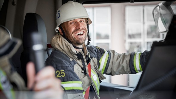 Feuerwehrmann sitzt lachend im Feuerwehrauto