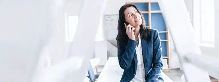 Frau sitzt auf dem Tisch und telefoniert
