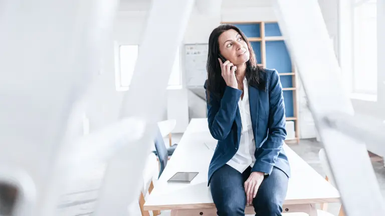 Frau sitzt auf dem Tisch und telefoniert