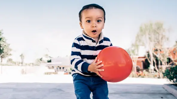 kleiner Junge hält roten Ball in der Hand