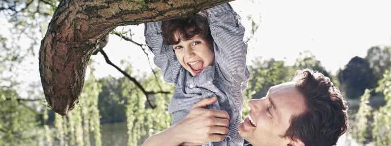 Mann hält Junge fest, der an einem Baum hängt