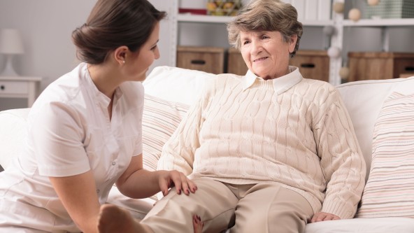 Ältere Frau wird von Pflegekraft am Bein untersucht