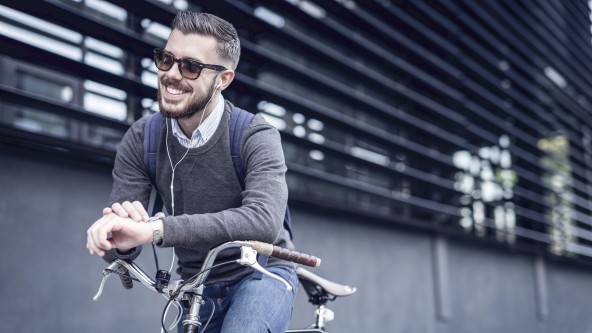 Mann mit Sonnenbrille sitzt lachend auf einem Fahrrad